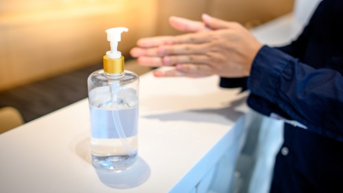 Hand sanitizer dispenser with a person in a shirt sanitizing their hands